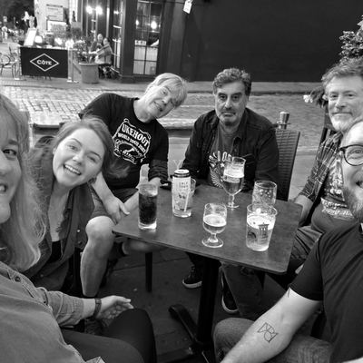 Post-gig pints and grins round a table outside.