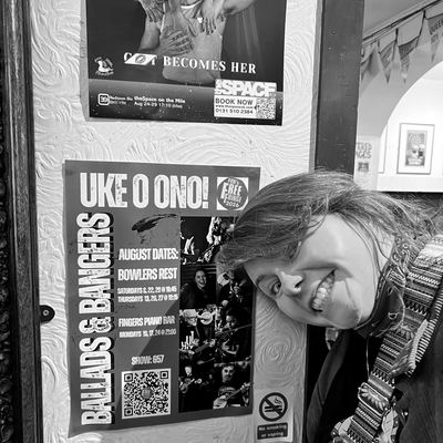 A band member pulling a face beside the Ballads & Bangers poster.