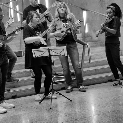 The band playing inside the Scottish Parliament, fiddle and ukuleles by the stairs.