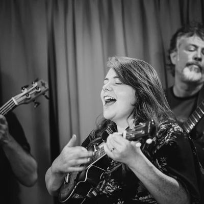A singer, eyes closed, belting out a chorus on ukulele.