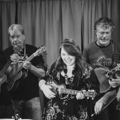 A singer at the centre of the band, ukuleles either side.