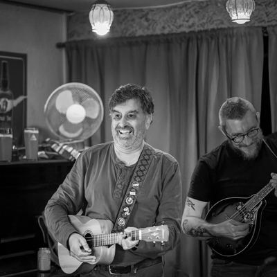 A grinning ukulele player at the front of the stage, mandolin behind.