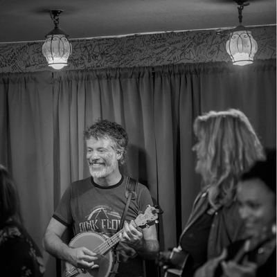 A banjo-ukulele player smiling across the stage.